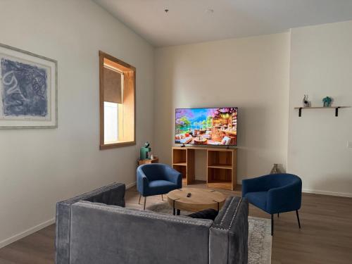 a living room with a couch and two chairs and a tv at Unicorn Zebra in Tucson