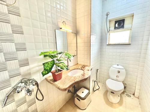 a bathroom with a toilet and a sink and a plant at Hotel El - Paso in Arambol