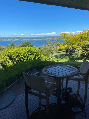 a table and chairs on a deck with a view of the water at Breathtaking views of Lake Taupo in Taupo