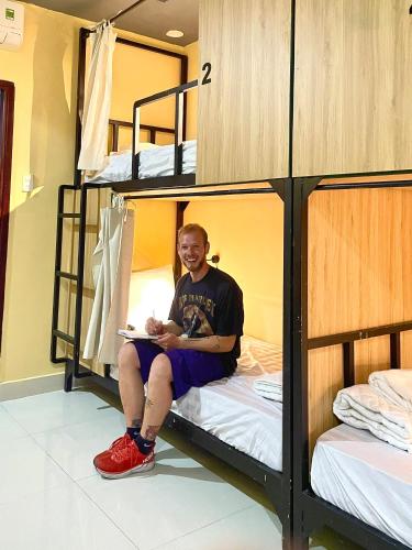 a man sitting on a bed in a bunk room at Dom Hostel Old Town Hoi An in Hoi An