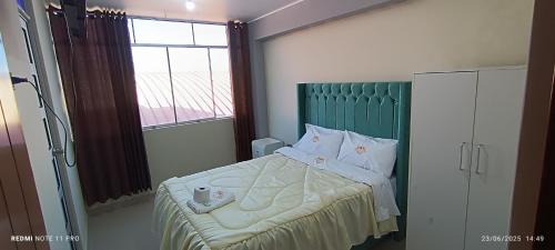 a bedroom with a bed with a green headboard and a window at Hotel Mirador Wanka in Huancayo