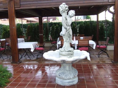 a statue of a woman sitting on top of a fountain at Hotel Senator in Slatina