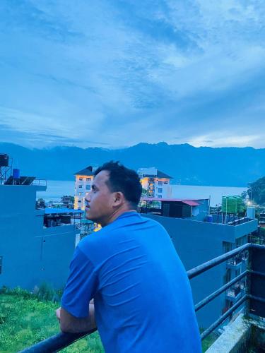 a man sitting on a balcony looking out over the water at Hotel Royal Orbit Pvt Ltd Pokhara in Pokhara