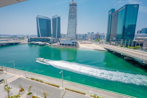 a boat in a river in a city with tall buildings at Canal View 1BR near Galleria Mall & Cleveland in Abu Dhabi