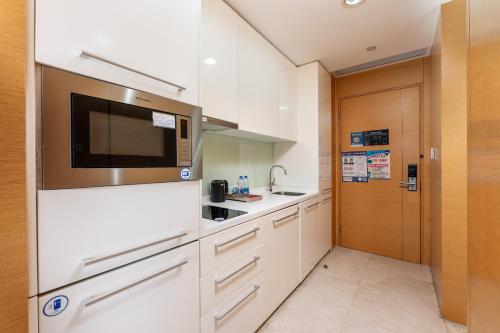 a kitchen with white cabinets and a microwave at Sheraton Guangzhou International Service Apartment (Pazhou Convention and Exhibition Center Branch) in Guangzhou