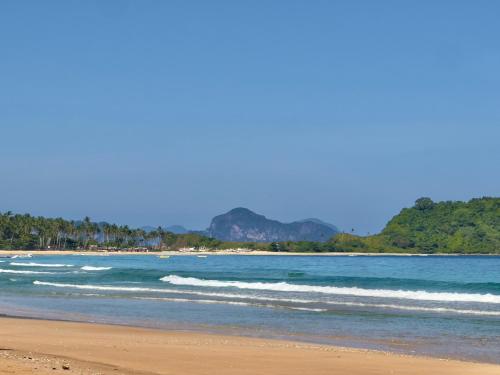a beach with the ocean and trees in the background at Eco Sanctuaries Nature Lodge Nacpan Beach, El Nido in El Nido