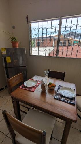 a wooden table with plates and a bowl of fruit on it at Apartamento Coco & Tambor in Livingston Izabal in Lívingston
