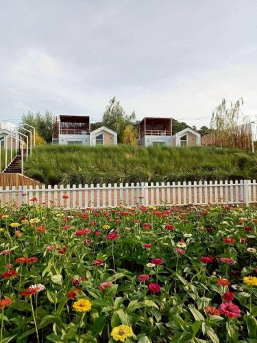 a field of flowers in front of a white fence at Nordic Hills Kanchanaburi in Ban Chek