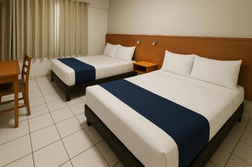 a hotel room with two beds and a table at Hotel Ana Isabel in Zamora de Hidalgo