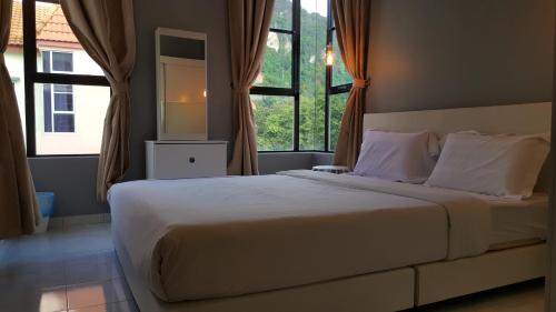 a bedroom with a large white bed with windows at Tulip Hotel in Ipoh