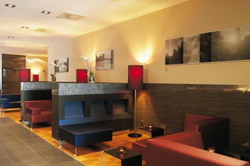 a lobby with a bar and couches and a fireplace at IntercityHotel Mannheim in Mannheim