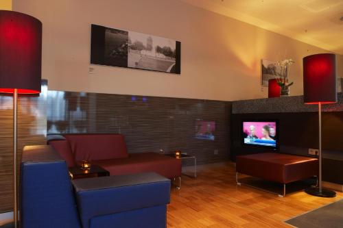 a living room with a couch and a tv at IntercityHotel Mannheim in Mannheim