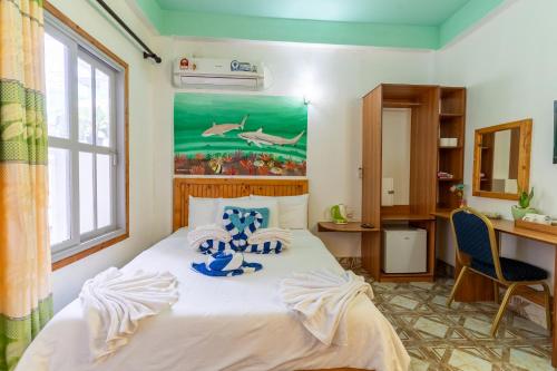 a bedroom with a bed with a painting on the wall at Olhumathi View Inn in Ukulhas
