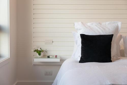 a white bed with a black pillow on it at No.8 Queenstown in Queenstown