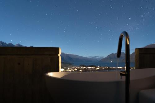 a bath tub at night with a view of the mountains at No.8 Queenstown in Queenstown