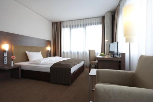 a hotel room with a bed and a chair at IntercityHotel Mannheim in Mannheim