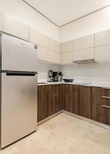 a kitchen with a white refrigerator and wooden cabinets at Hotel zone - Private Jacuzzi & Free Beach Club in Tulum