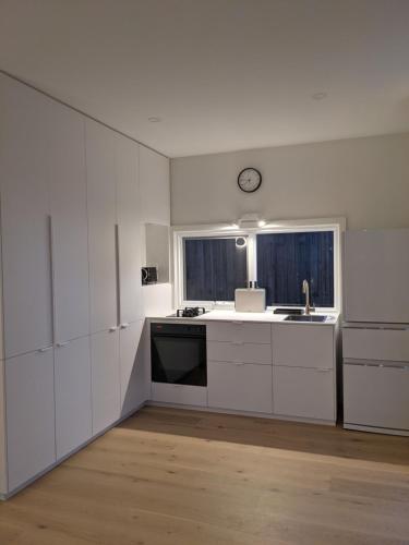 a kitchen with white cabinets and a clock on the wall at The White House in Suffolk Park