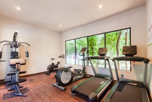 a gym with two treadmills and two exercise bikes at FamilyFriendly10min to BeachWIFI200MB6PoolsGym in Playa del Carmen