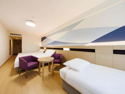 a hotel room with two beds and a table and purple chairs at Hotel Dream Gate Maihama in Chiba