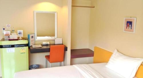a room with a bed and a desk with a mirror at C2 Residence Hotel in Lampang
