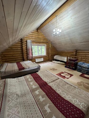 ein Schlafzimmer in einer Blockhütte mit einem Bett und einem Fenster in der Unterkunft Ene sai in Karakol