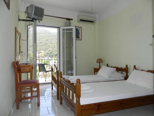 a bedroom with two beds and a balcony at Logaras Apartments in Ayia Evfimia