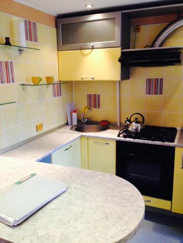 a kitchen with yellow cabinets and a counter top at Apartment on Druzhby 4 in Perm