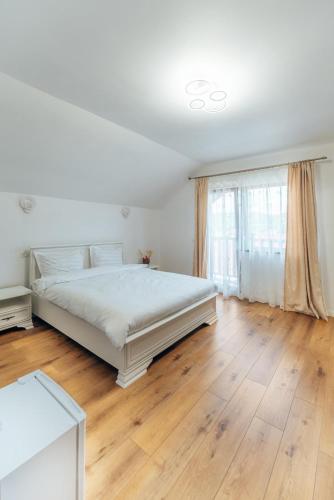 a white bedroom with a bed and a window at Casa Carmen in Poienile Izei