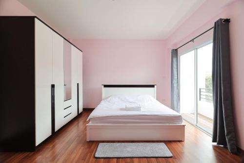 a bedroom with a white bed and a large window at The Comfort house near CMU in Chiang Mai
