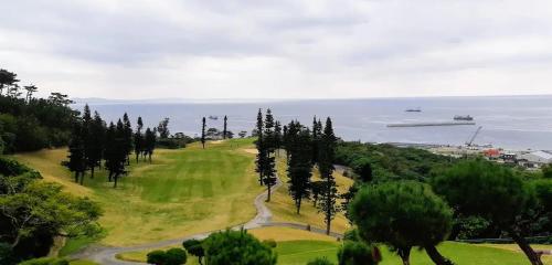 a golf course with trees and the ocean in the background at ハイ沖縄金武店トイレお風呂共用 プレオープン中駐車場有 ペット同伴可能長期滞在可能2025年10月より車貸し出しサービス有希望であればお申し付けください in Kin