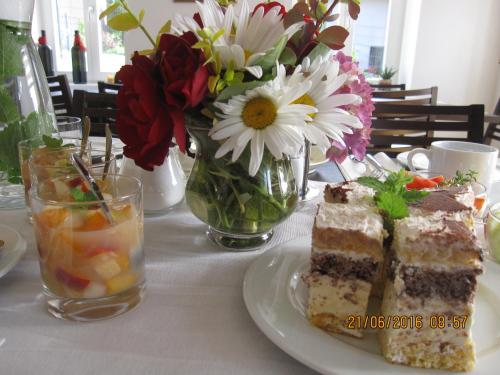 a table with a plate of cake and a vase of flowers at Villa zur Schmied'n in Ehrenhausen