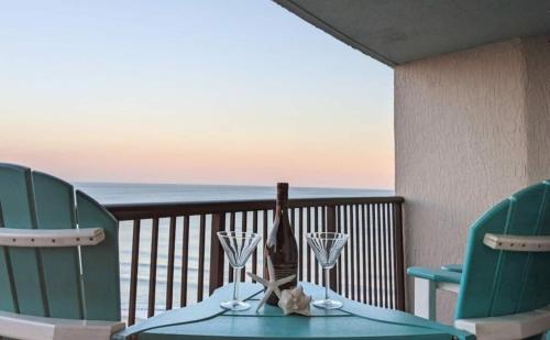 a table with a bottle of wine and two glasses on a balcony at Ocean View, Near Boardwalk, Pool, Hot Tub in Myrtle Beach