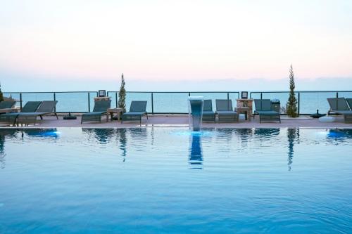 a swimming pool with chairs and the ocean in the background at CLASS PREMİUM hotel in Çanakçılar