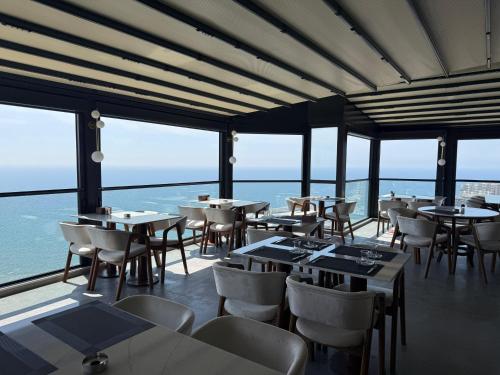 a restaurant with tables and chairs and the ocean at CLASS PREMİUM hotel in Çanakçılar
