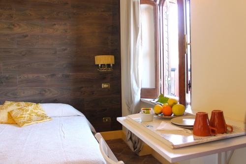 タオルミーナにあるCasa Via del Mareのベッド1台、テーブル(フルーツ付)が備わる客室です。
