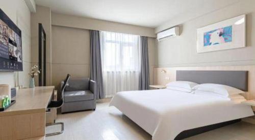 a bedroom with a large white bed and a desk at Jinjiang Inn Weihai High Speed Qingdao South Road in Weihai