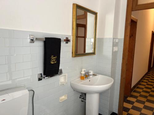 Un baño blanco con lavabo y espejo. en Appartamento Porretta Sweet Soul, en Porretta Terme