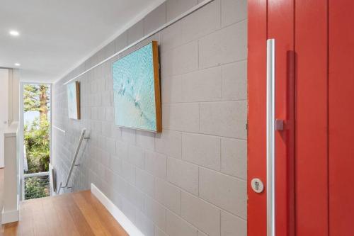a hallway with a red door and a brick wall at The Bungan - Beachfront W Access To Bungan Beach in Newport