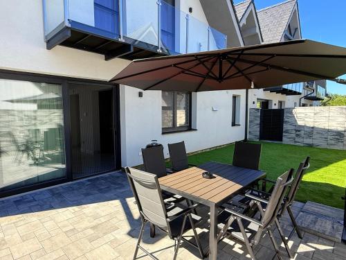 a wooden table with chairs and an umbrella on a patio at Villa Lilien Residence Tatry in Veľká Lomnica