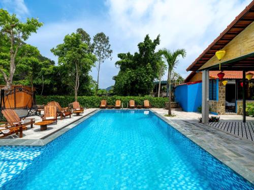 Una piscina con tumbonas al lado de una casa. en Cozy Son Hotel, en Ninh Binh