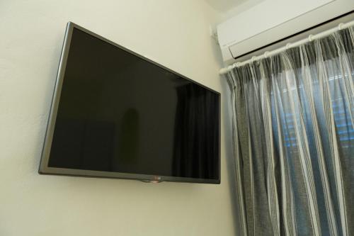 TV de pantalla plana colgada en una pared junto a una ventana en Arpistis apartments koufonisia en Koufonisia