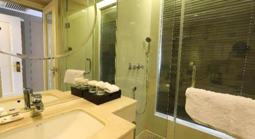 a bathroom with a shower and a sink and a tub at Jinjiang Metropolo Hotel Classiq YMCA People Square in Shanghai