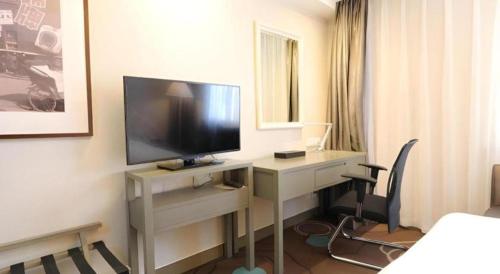 a hotel room with a desk with a television on it at Jinjiang Metropolo Hotel Classiq YMCA People Square in Shanghai