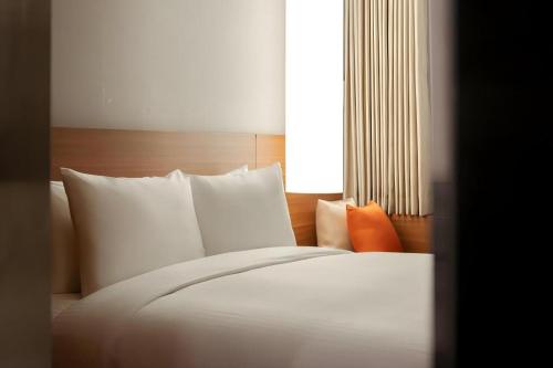 a white bed with white pillows and a window at Top Cloud Hotel Iksan in Iksan