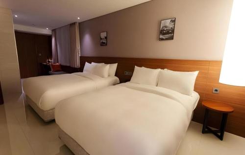 a hotel room with two beds and a table at Top Cloud Hotel Iksan in Iksan