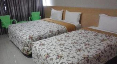 two beds in a hotel room with green chairs at Fafa Hill Hotel and Resort in Bogor
