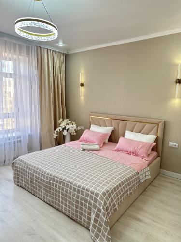 a bedroom with a large bed with pink pillows at ПОЛНОЦЕННАЯ ТРЕХКОМНАТНаЯ ЛЮКС in Kokshetau