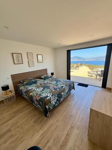 a bedroom with a bed and a large window at Villa de Luxe avec Piscine à débordement chauffée à Porticcio in Porticcio