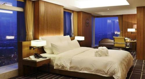 a bedroom with a bed and a desk and a chair at Chongqing The Lotus Hotel in Chongqing